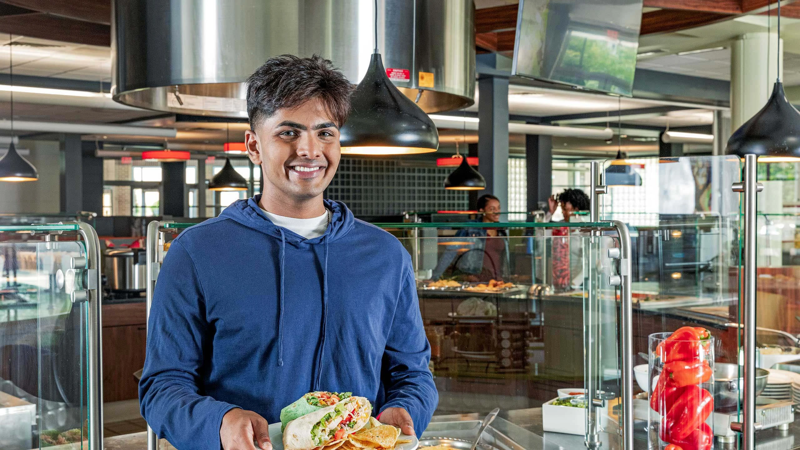 Student smiling while standing in the middle of cafeteria